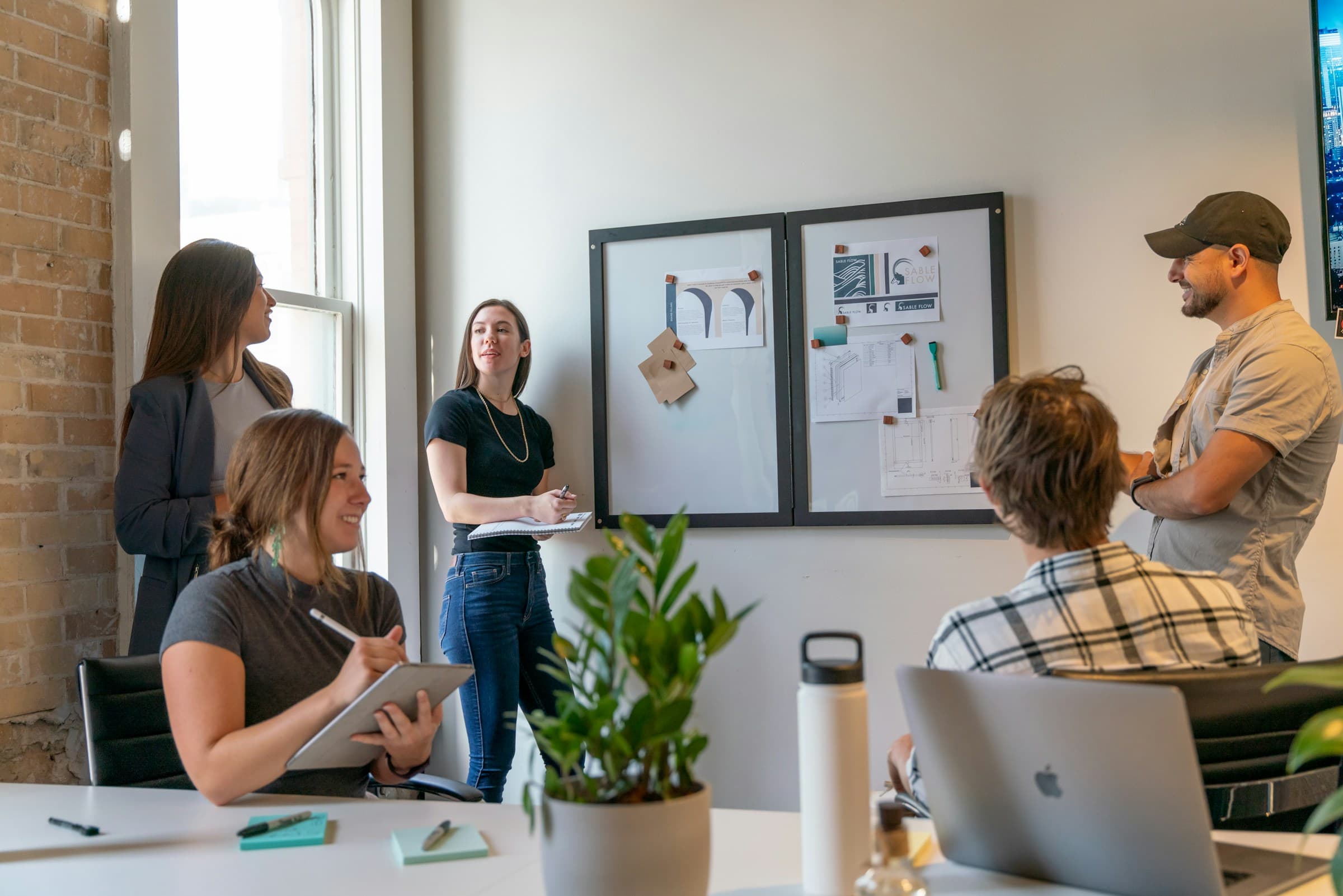 A team meeting in front of a whiteboard in a sunlit office